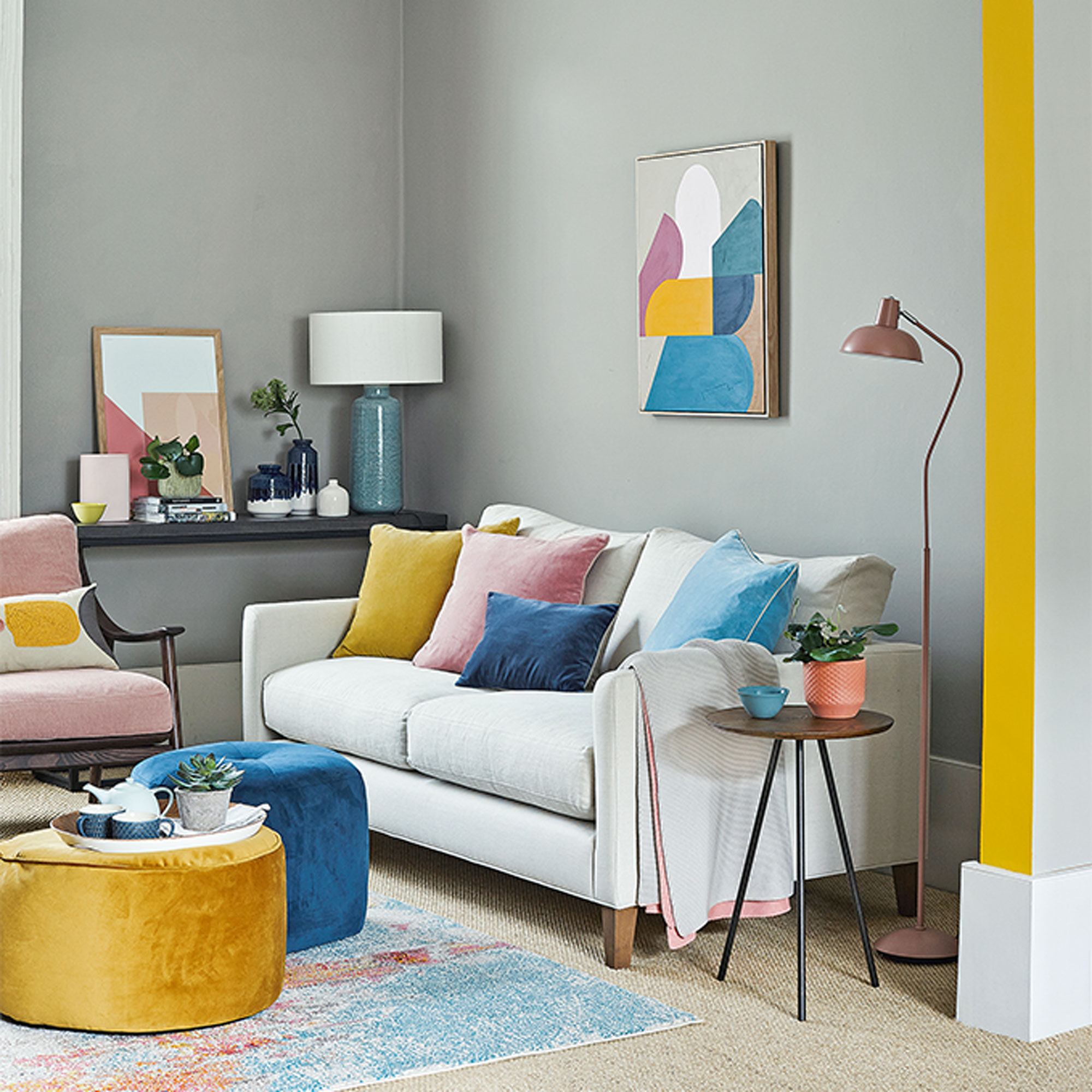ruang tamu abu-abu dengan aksen kuning dan sofa netral
