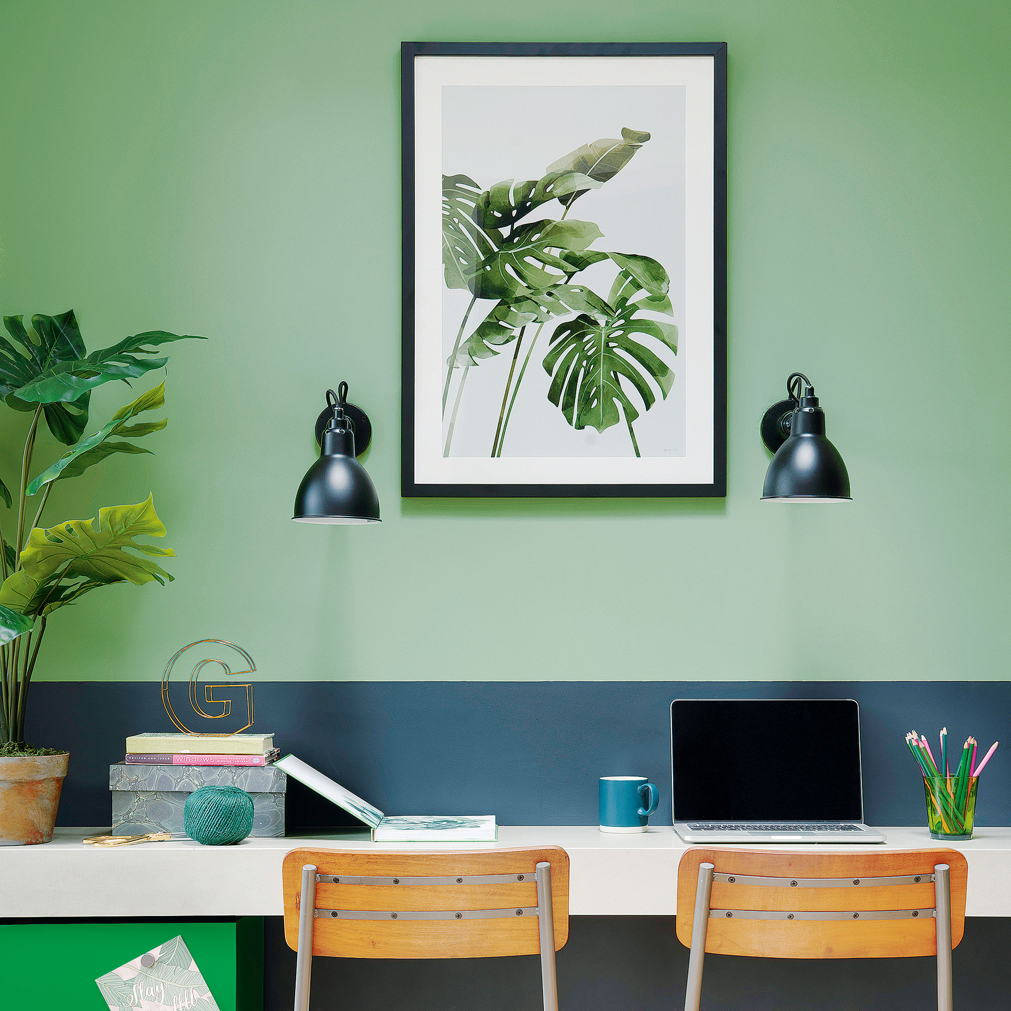 Kantor rumah dengan dua dinding berwarna hijau, dua lampu dinding, dan cetakan botani