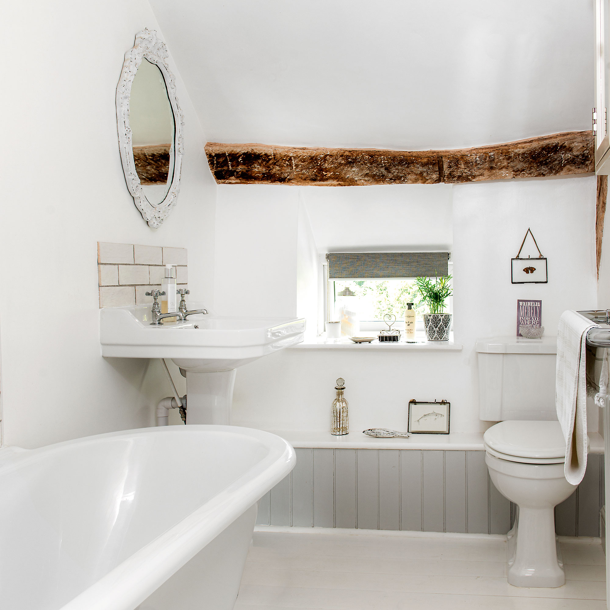 Kamar mandi putih dengan bathtub berdiri sendiri dan langit-langit balok kayu