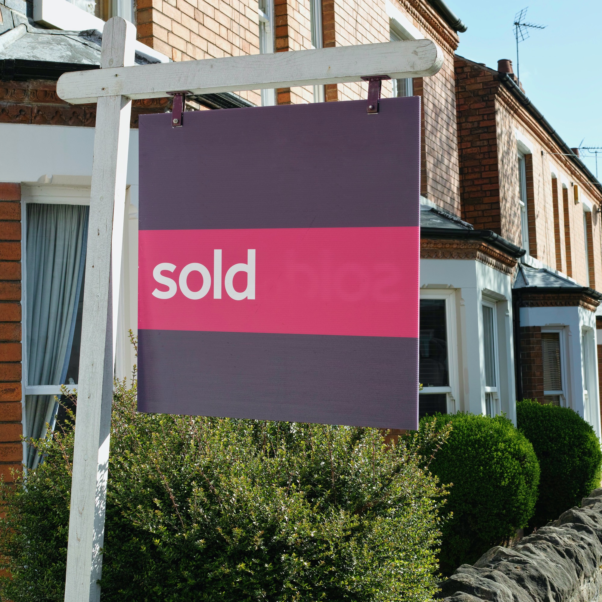 Rumah pinggiran kota Inggris dengan tanda 'terjual'.